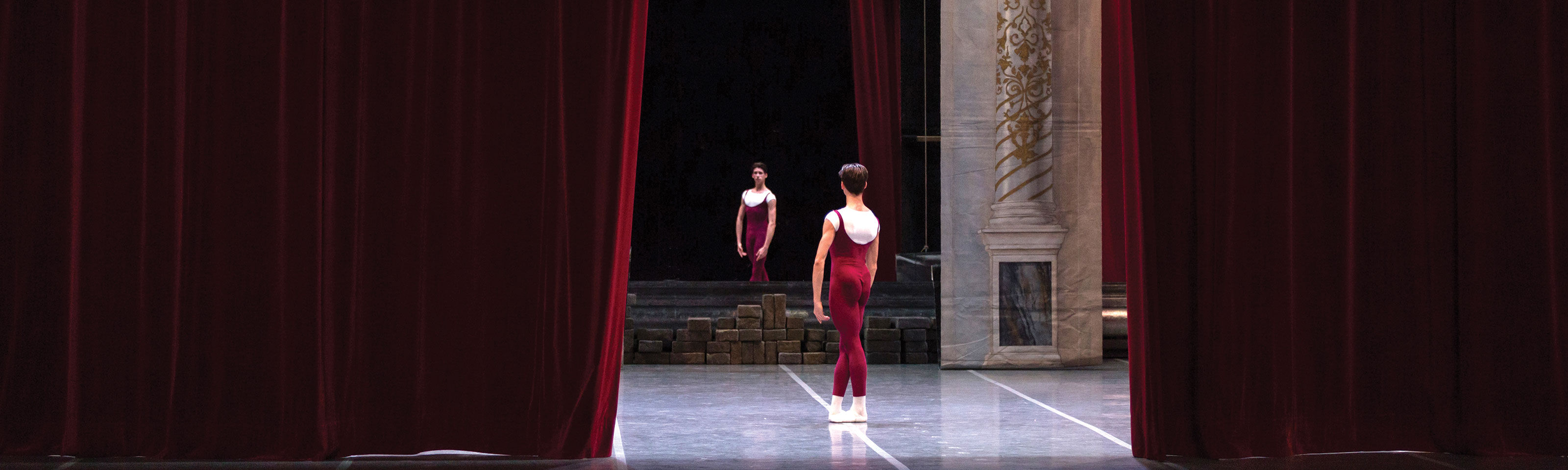 Giovane ballerino in accademico rosso pronto in scena all'apertura di sipario